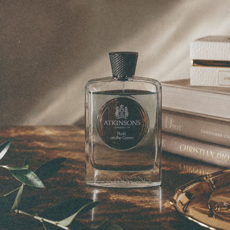 Atkinsons Posh on the Green Eau de Parfum bottle on a desk with books and olive leaves