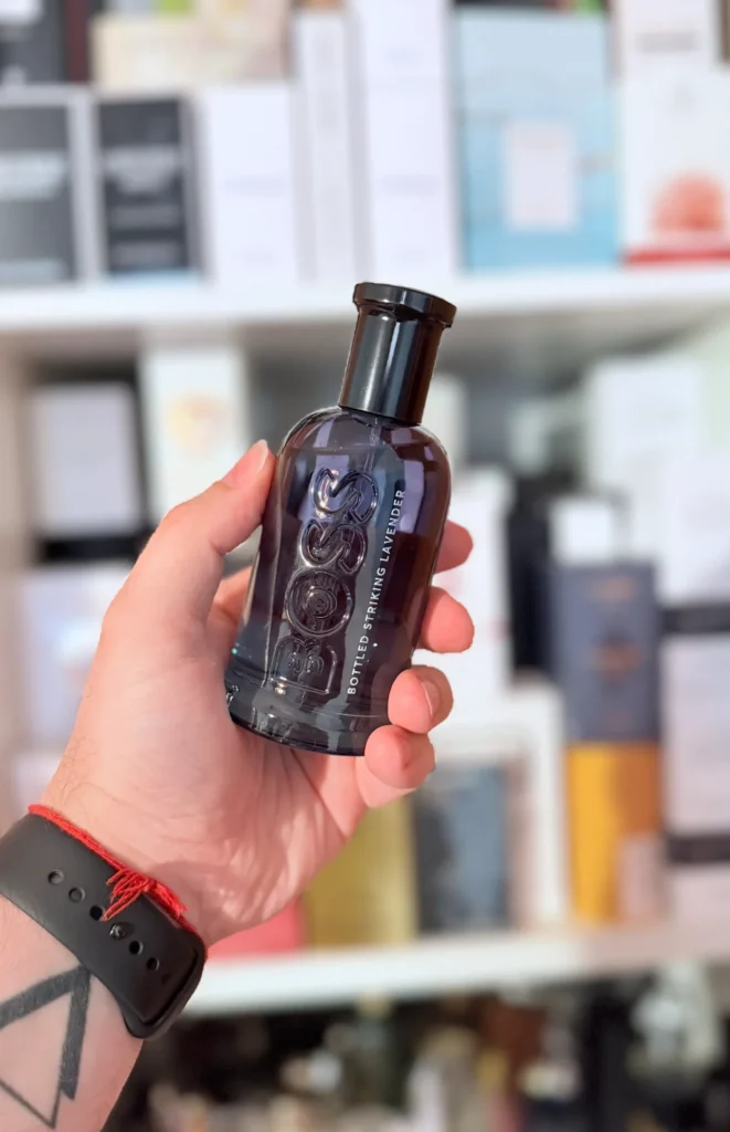 BOSS Bottled Striking Lavender perfume bottle held in front of a fragrance collection