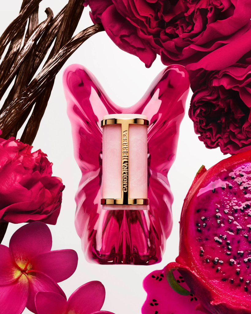 Carolina Herrera La Bomba perfume bottle with peonies, plumeria, dragon fruit and vanilla pods flat lay