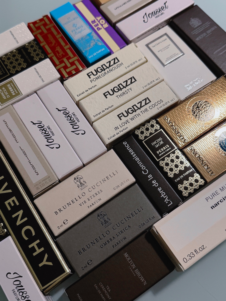 Close cropped flat lay of niche perfume sample boxes including Fugazzi, Brunello Cucinelli and Atkinsons Parfum Intense