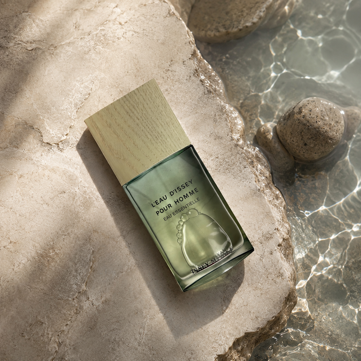 Issey Miyake L’Eau d’Issey Pour Homme Eau Essentielle bottle beside clear water and pale rocks