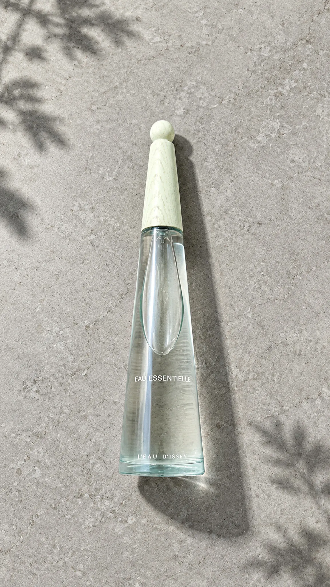 L’Eau d’Issey Eau Essentielle perfume bottle on a stone surface in natural light