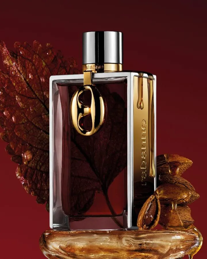 Rabanne Brutalist Amber bottle with bitter almonds and a dark leaf on a red background