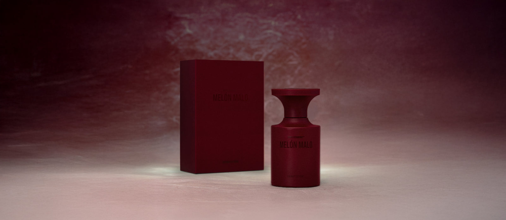 Melon Malo perfume bottle and box in a dark red setting