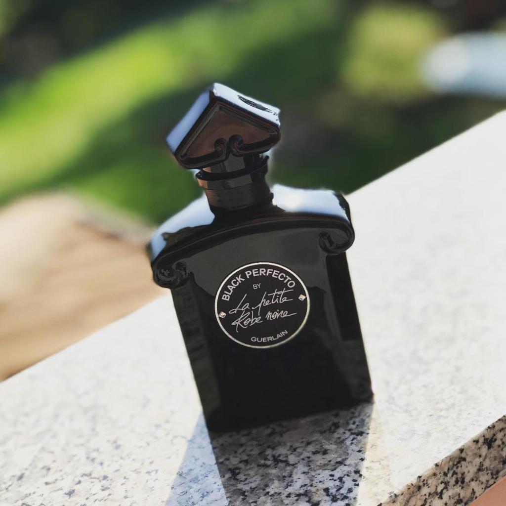 Guerlain Black Perfecto by La Petite Robe Noire black bottle photographed outdoors.