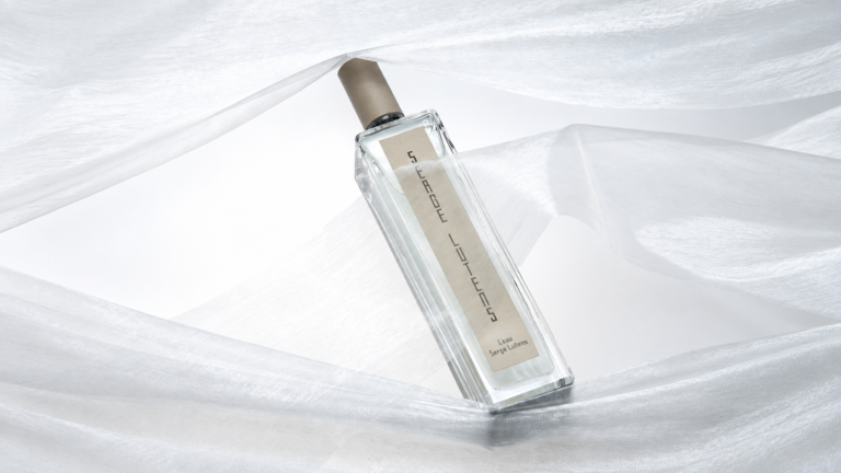 L'Eau Serge Lutens Eau de Parfum bottle among folds of white fabric.