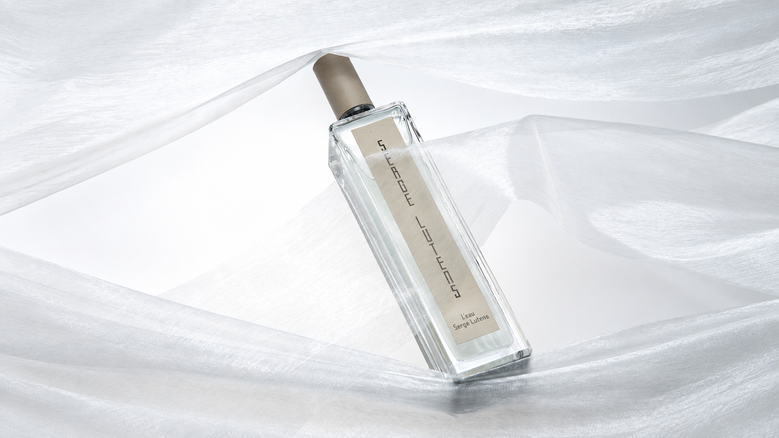 L'Eau Serge Lutens Eau de Parfum bottle among folds of white fabric.