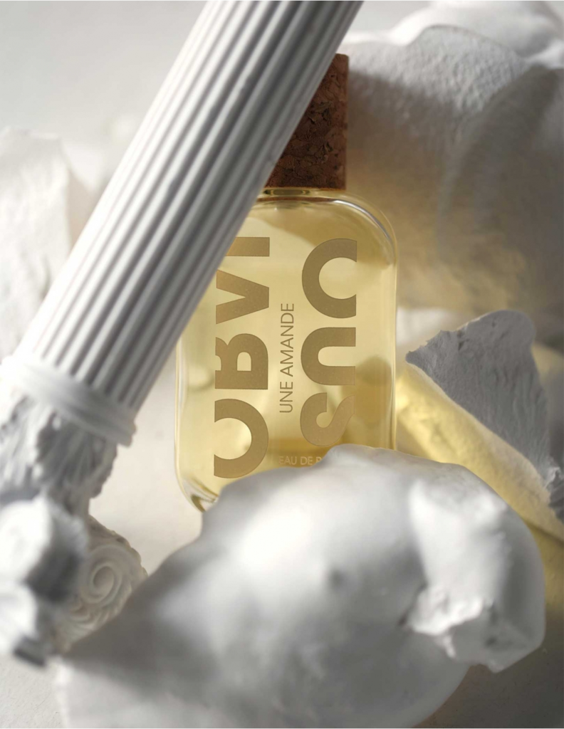 Obvious Une Amande bottle arranged with white sculptures and a fluted column