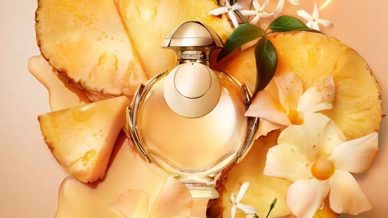Rabanne Olympea Elixir perfume bottle surrounded by pineapple and white flowers