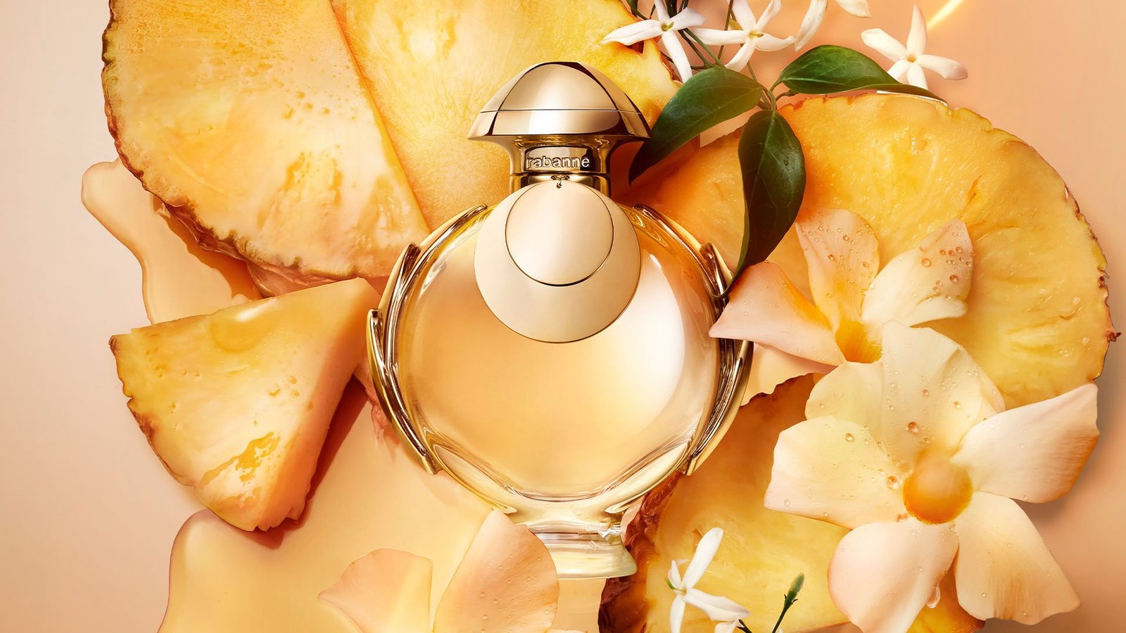 Rabanne Olympea Elixir perfume bottle surrounded by pineapple and white flowers