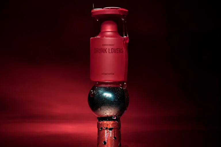 Drunk Lovers Extrait Extrême by BORNTOSTANDOUT, a red perfume bottle in a dramatic dark red setting