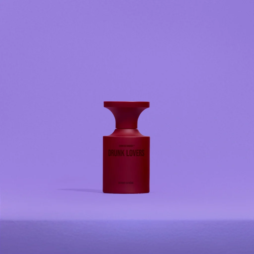 Red bottle of BORNTOSTANDOUT Drunk Lovers Extrait Extrême perfume against a minimalist lavender background