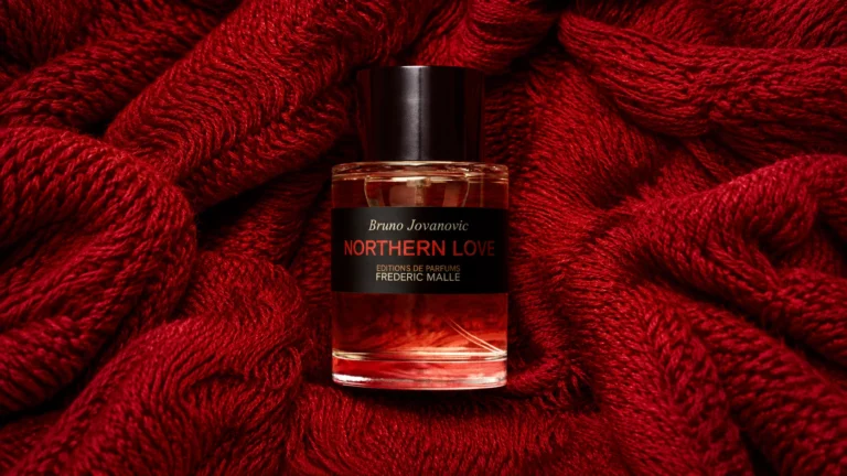 Frédéric Malle Northern Love perfume by Bruno Jovanovic resting on rich red knitted fabric.