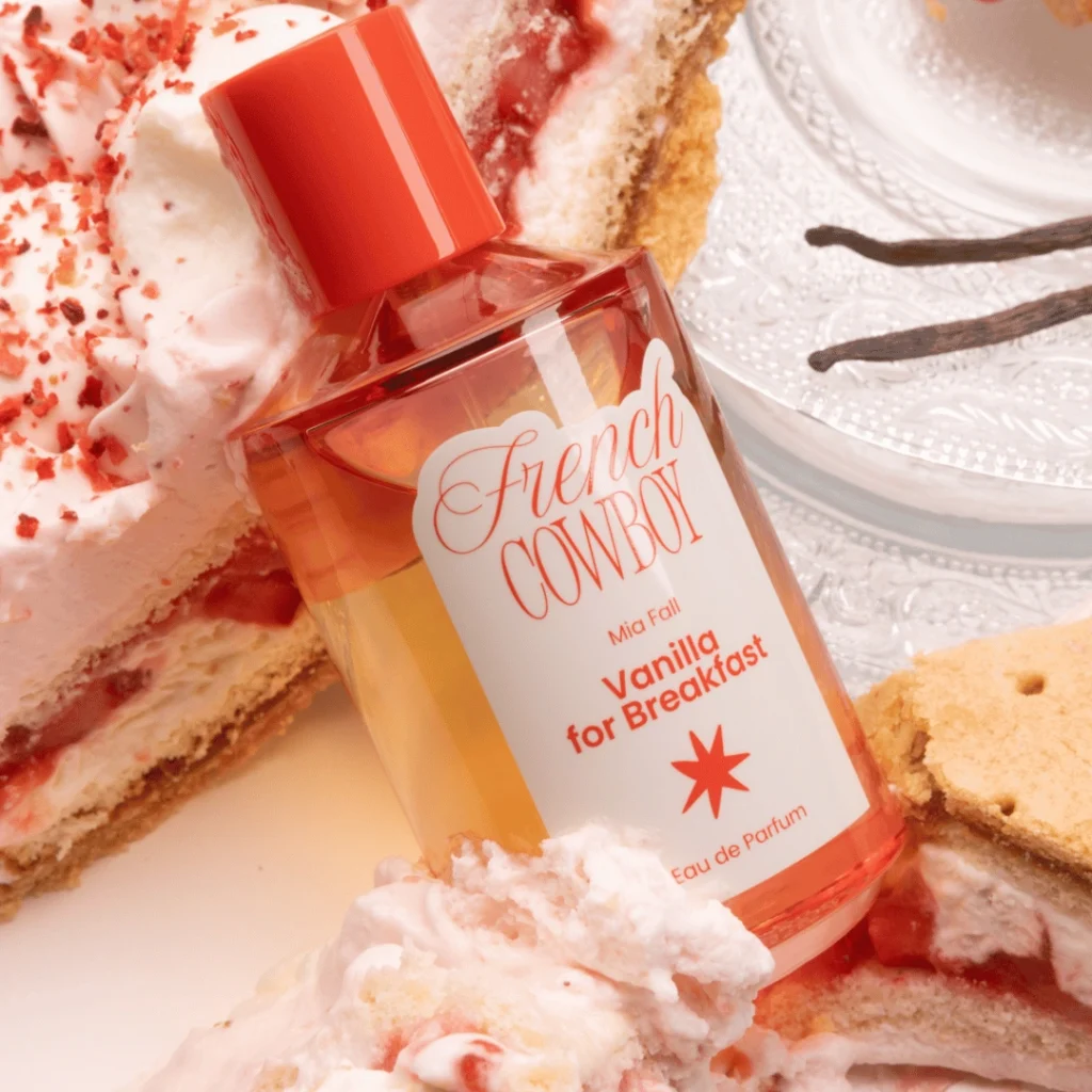 French Cowboy Vanilla for Breakfast perfume bottle resting among strawberry cake, whipped cream and vanilla pods.