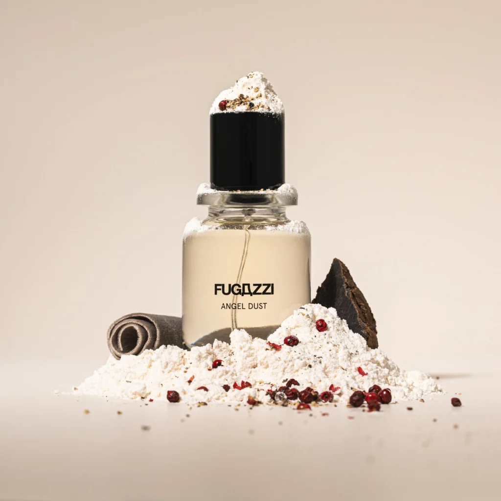 Fugazzi Angel Dust Extrait de Parfum bottle with black cap surrounded by white powder and red peppercorns