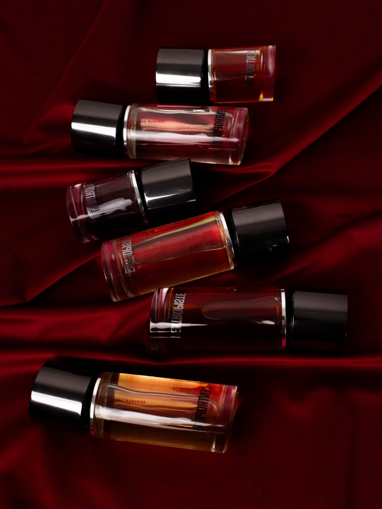 Several L'Entropiste perfume bottles arranged on deep red fabric