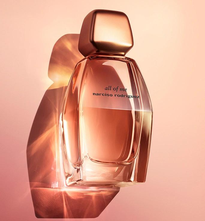Narciso Rodriguez All of Me perfume bottle in warm peach light, casting a shadow on the background.