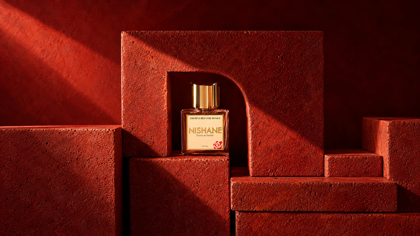 Nishane Thorns Become Roses bottle inside a terracotta arch surrounded by textured red blocks
