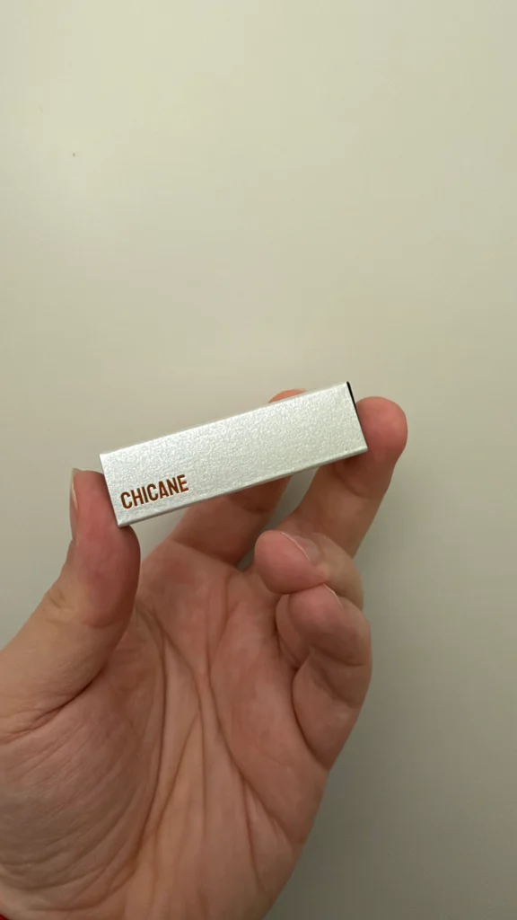 NOTHIN'ELSE Chicane perfume sample box with metallic silver packaging and Chicane lettering, held in hand.
