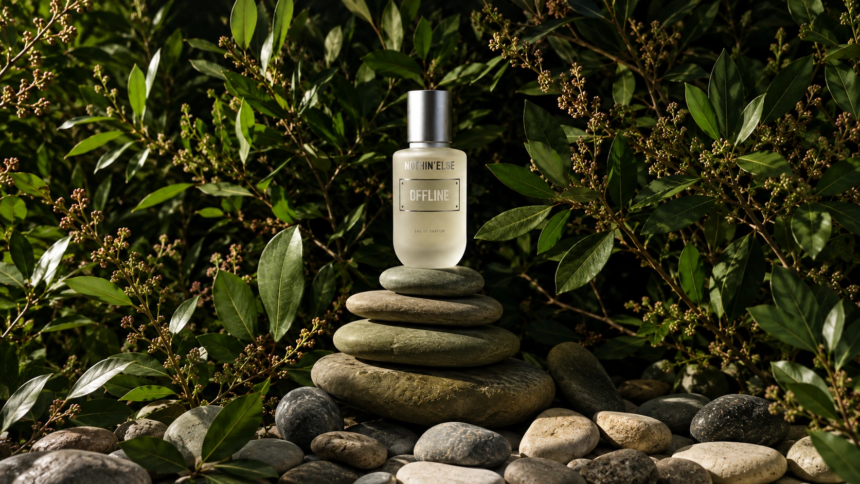 NOTHIN’ELSE Offline perfume bottle on stacked stones surrounded by green foliage