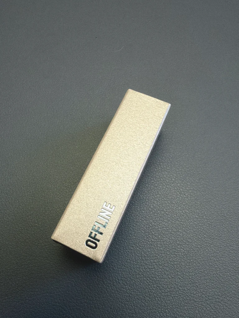 Silver NOTHIN’ELSE Offline sample box lying diagonally on a dark desk