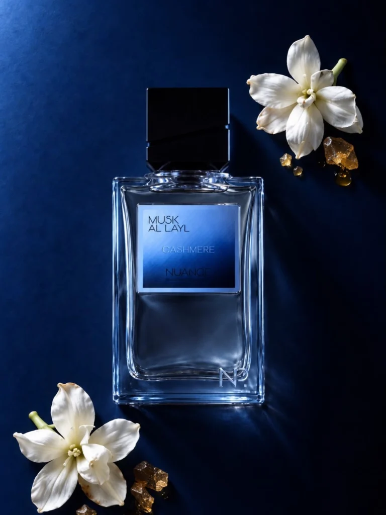 Nuance Parfums Musk Al Layl perfume bottle against a deep blue background with white flowers and golden resin.