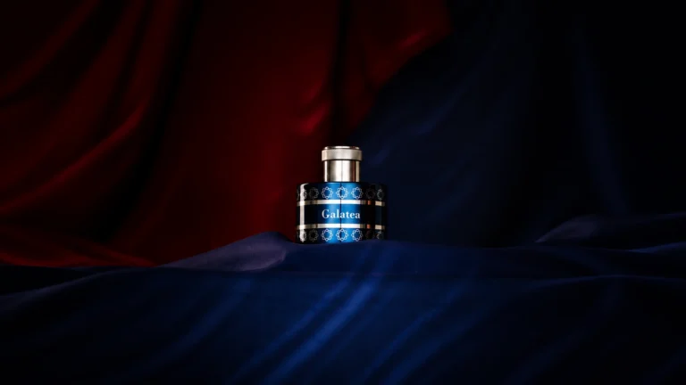 Pantheon Roma Galatea Extrait de Parfum in a midnight-blue bottle surrounded by dark blue fabric against a dramatic burgundy background.
