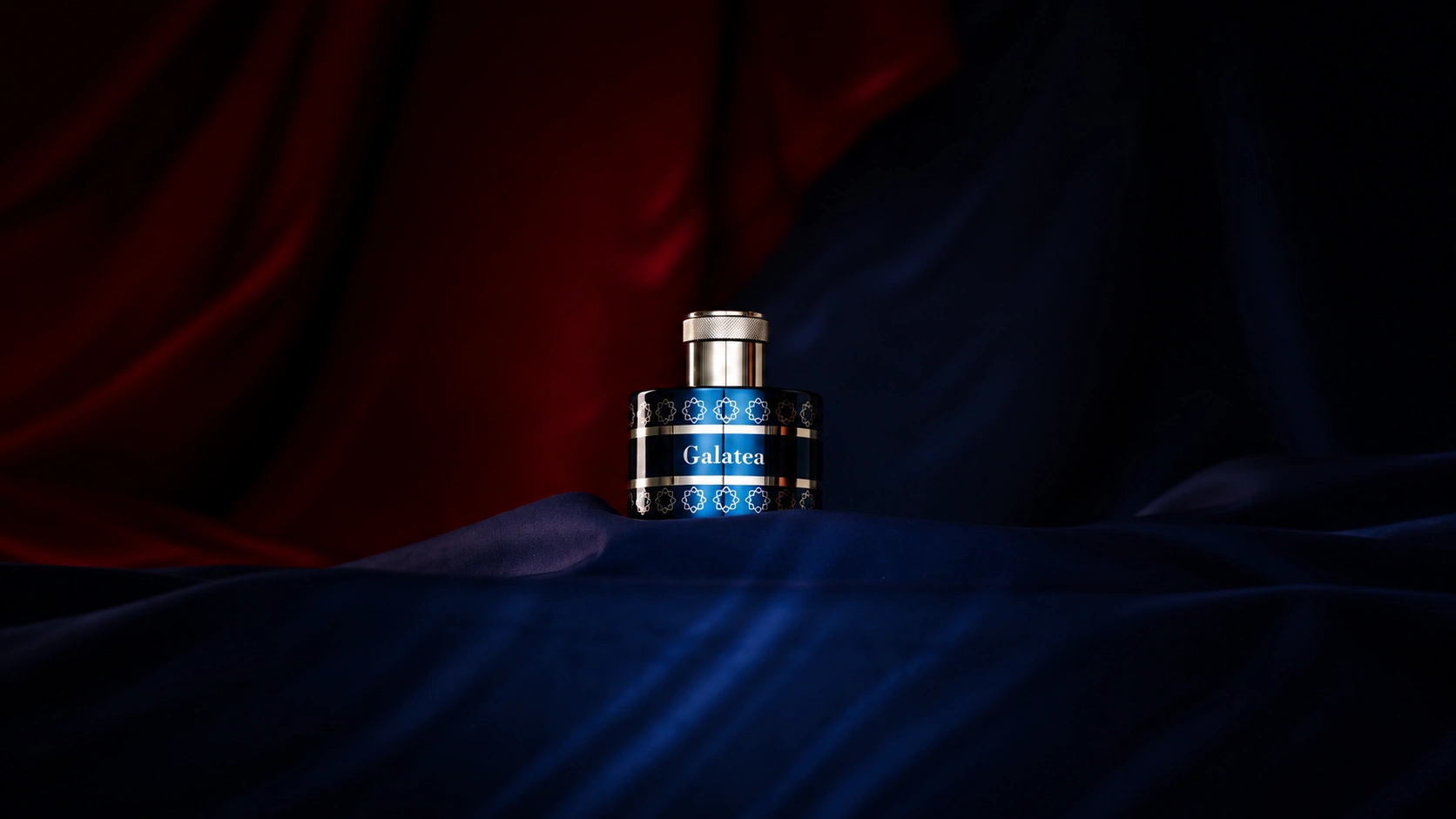 Pantheon Roma Galatea Extrait de Parfum in a midnight-blue bottle surrounded by dark blue fabric against a dramatic burgundy background.