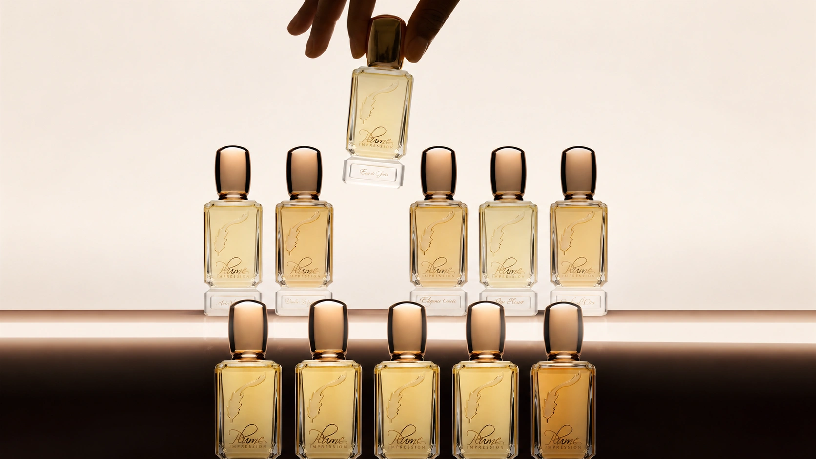 Plume Impression luxury perfume collection displayed in golden glass bottles, with one fragrance being lifted by hand.