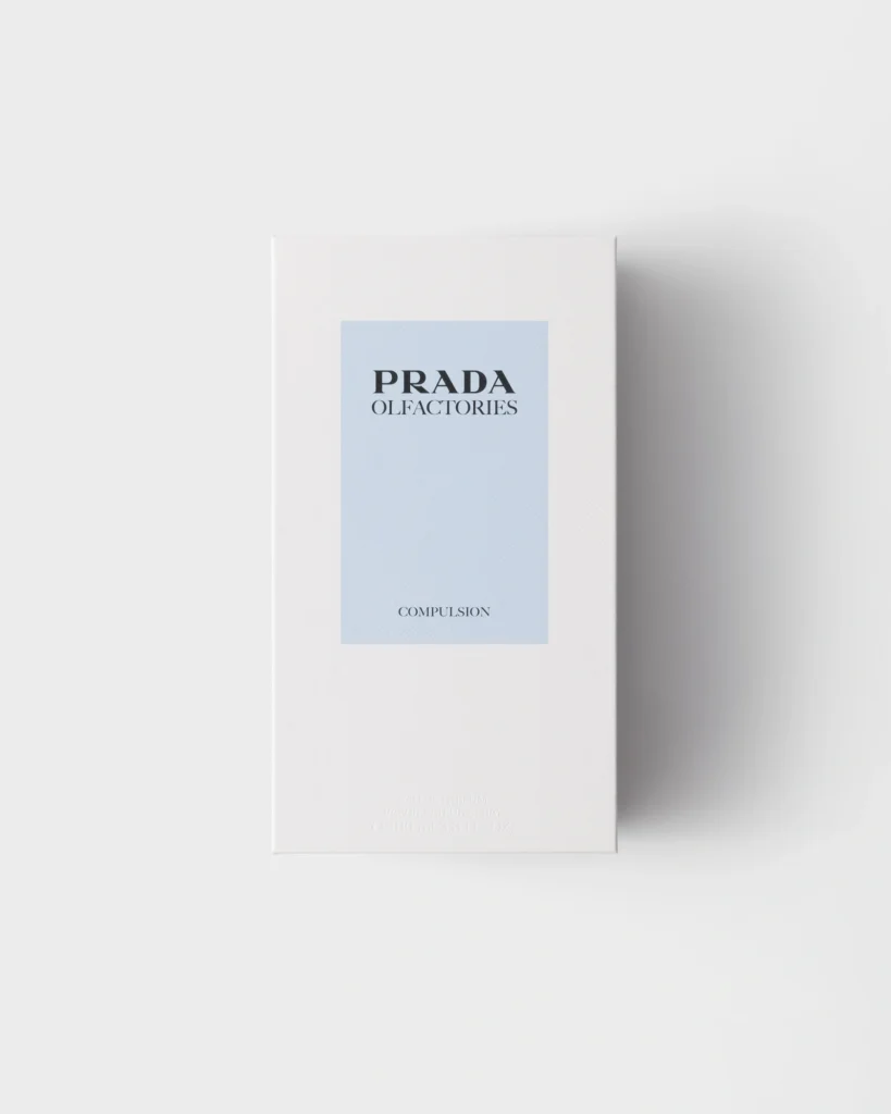 Prada Olfactories Compulsion fragrance packaging featuring a minimalist white box with pale blue label.
