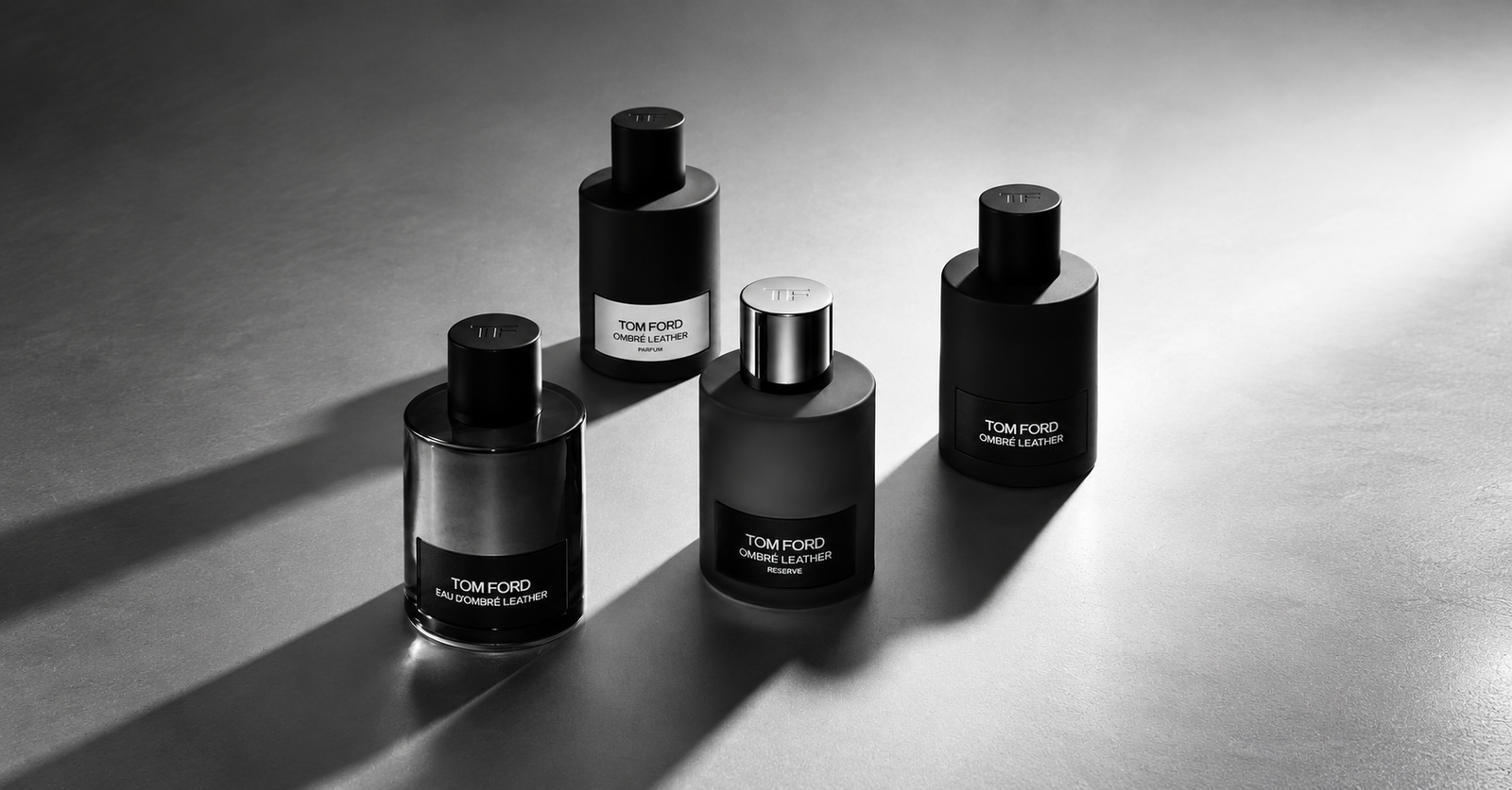Four Tom Ford Ombré Leather fragrances arranged in a monochrome editorial composition with dramatic lighting.