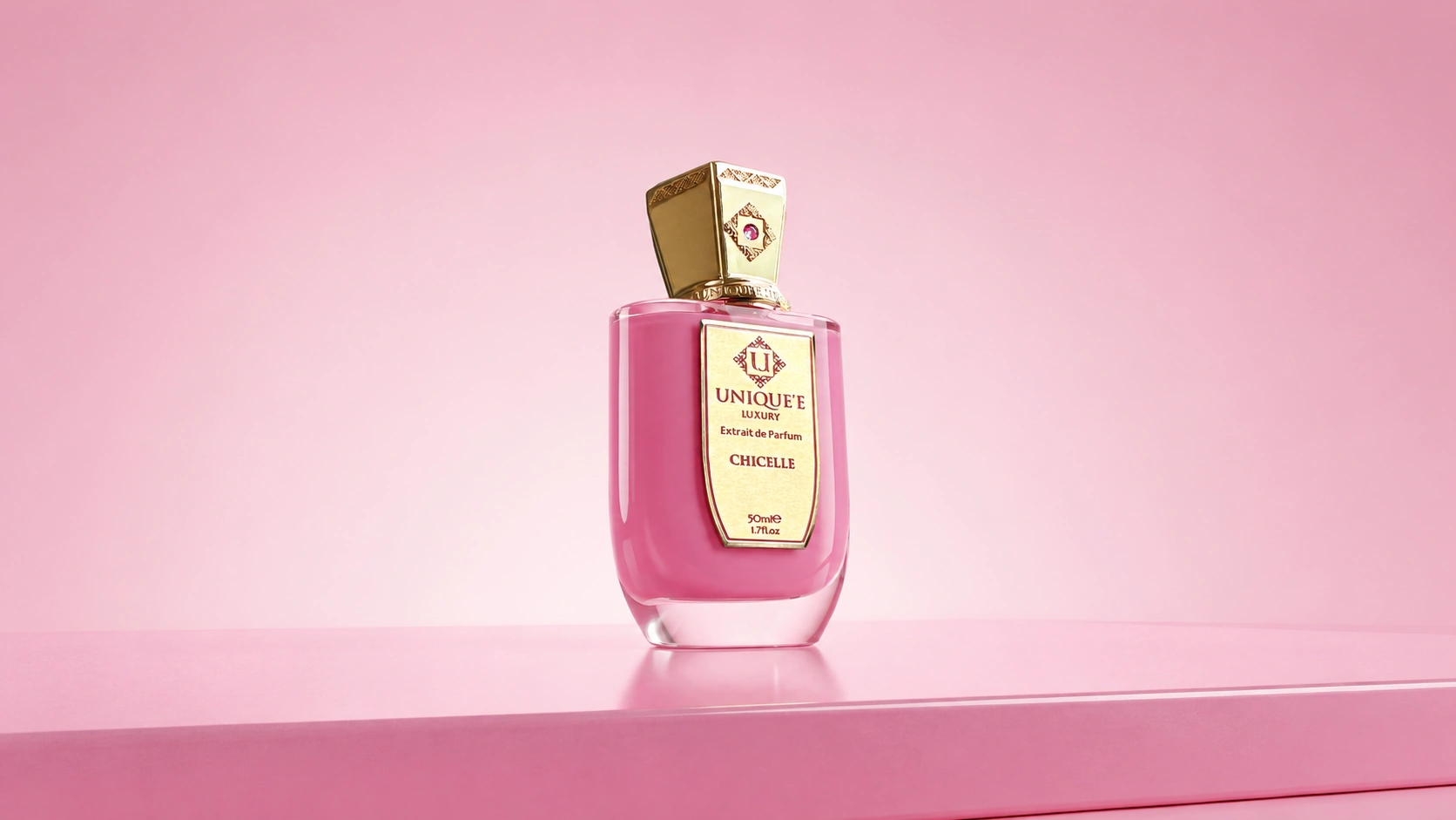 Chicelle perfume bottle by Unique’e Luxury centered against a wide pink background with a reflective surface.